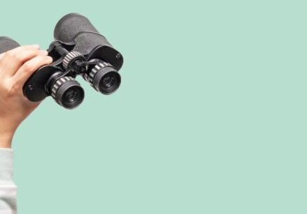 hand holding binoculars on green background for blog post "Search Engine Optimization (SEO) Resources"
