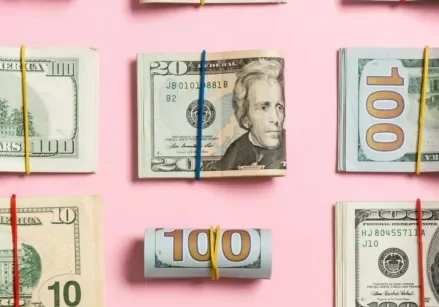 folded wads of money on a pink background