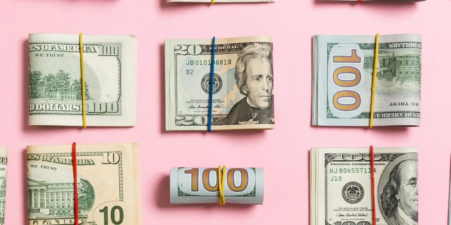 folded wads of money on a pink background