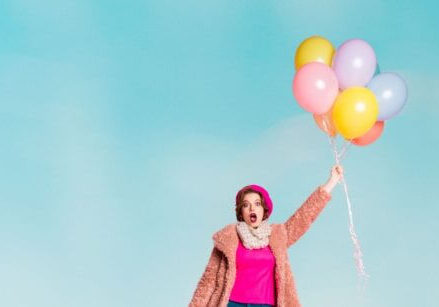 woman floating up in the sky holding on to a bundle of balloons