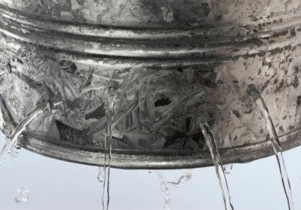 a galvanized bucket with holes leaking out streams of water