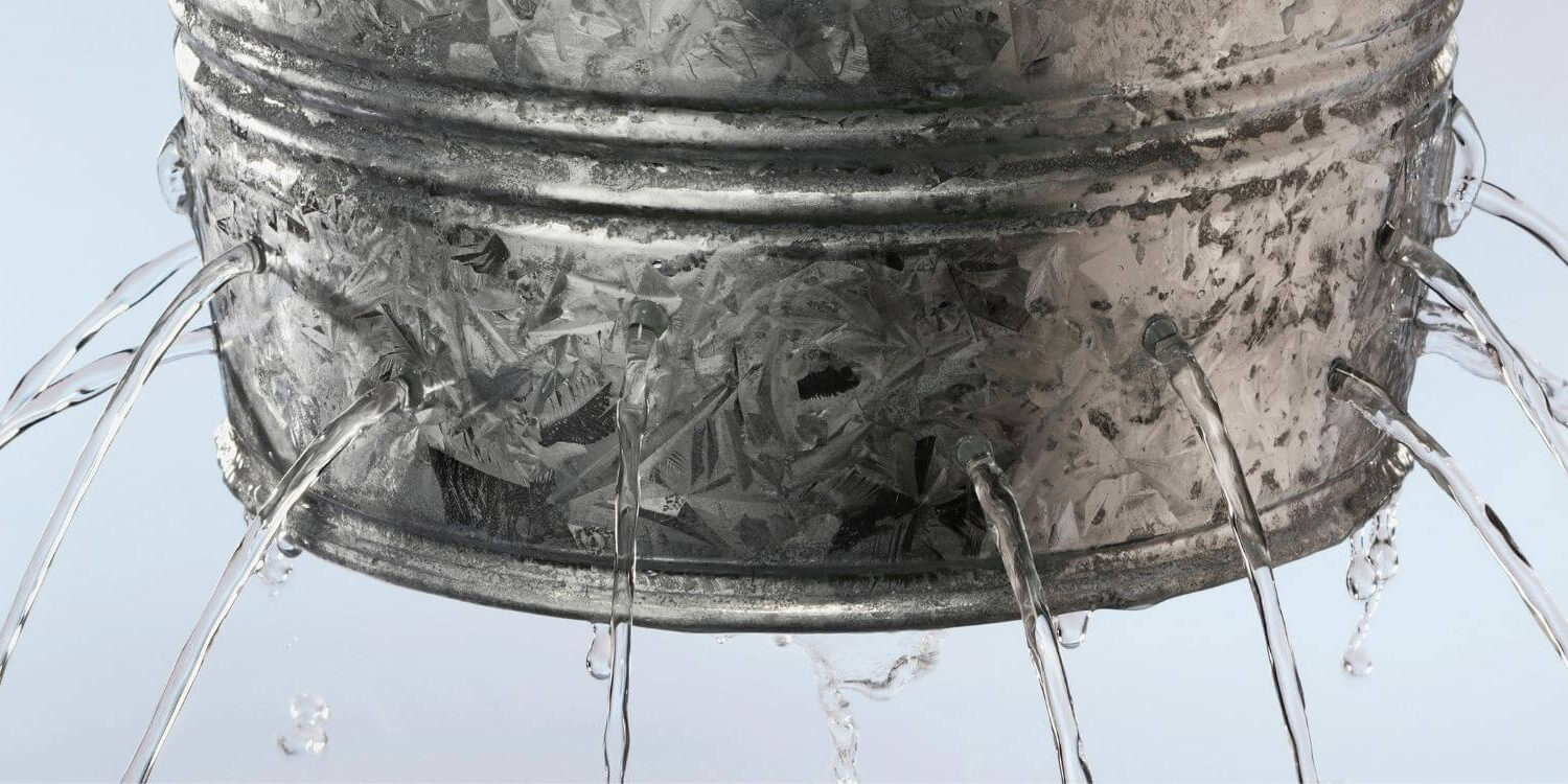 a galvanized bucket with holes leaking out streams of water