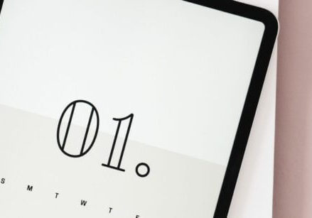 ipad with the number 01 on it laying on a blush pink desk with white desk accessories