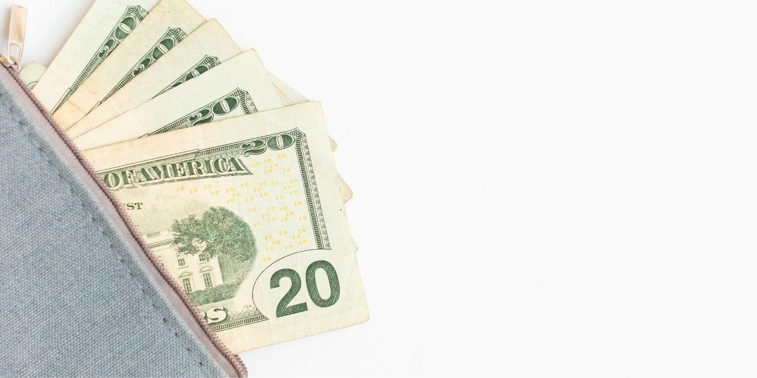 a gray zipper pouch with money poking out of it on a white background