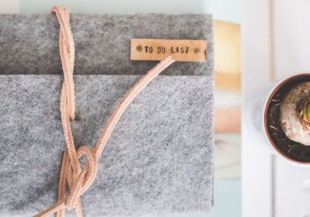 gray wool journal cover wrapped in leather stacked over a notebook in an organized pile next to an orchid