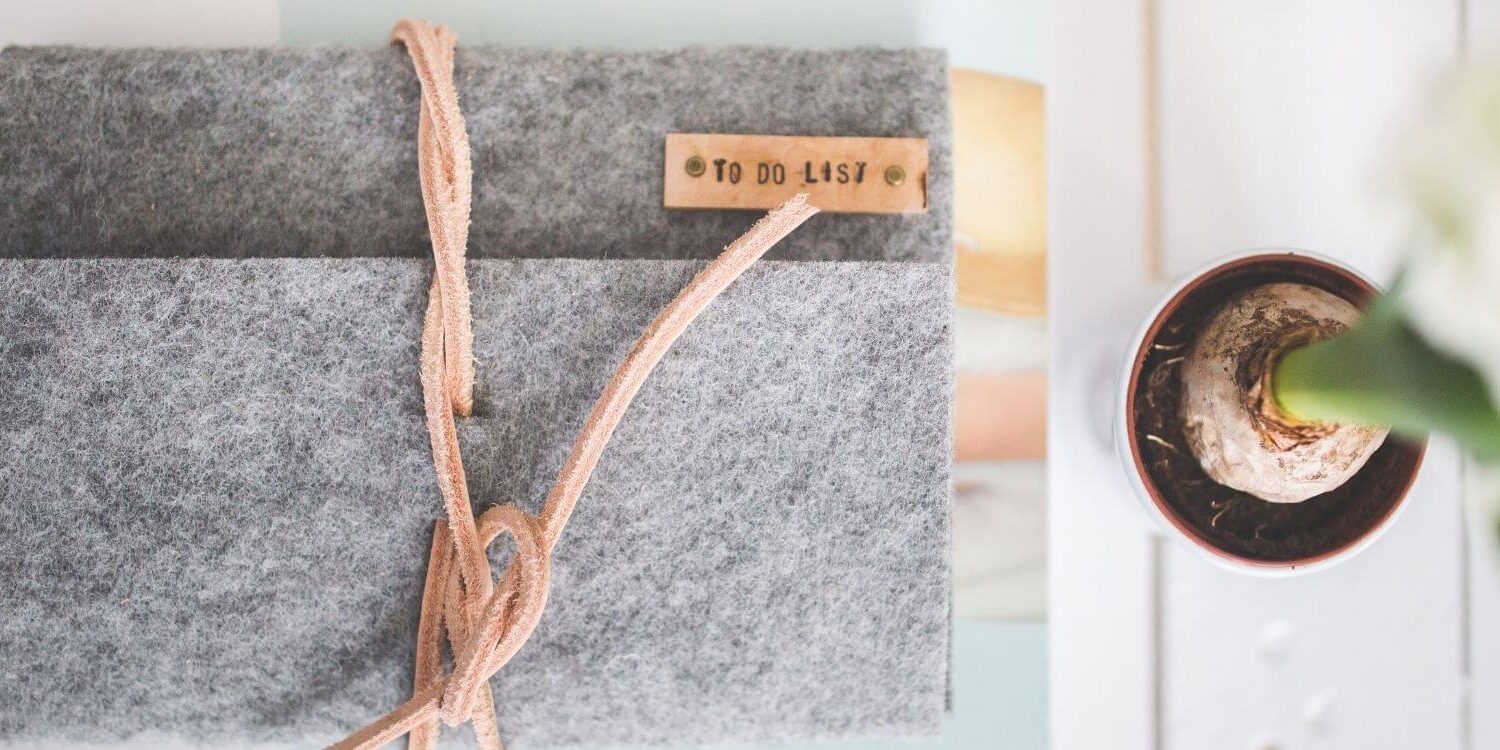 gray wool journal cover wrapped in leather stacked over a notebook in an organized pile next to an orchid