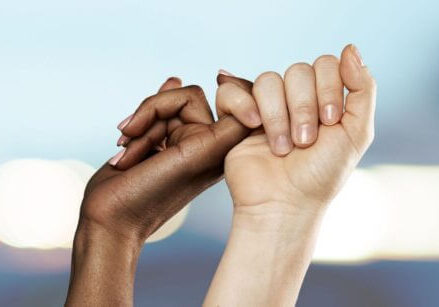 image of two women doing a pinky promise against a blurry blue background
