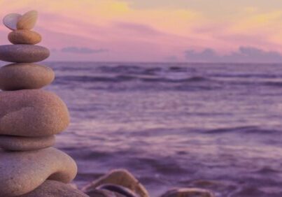 a stack of rocks balanced against an ocean at sunset - representing balanced not busy