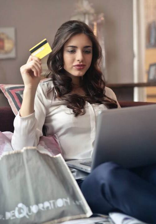 Woman holding a credit card making a purchase on her laptop.