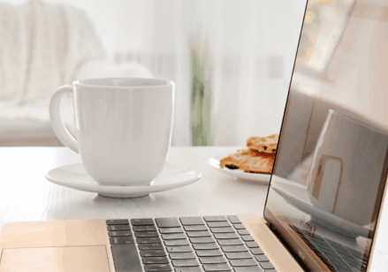 laptop and a white coffee mug on a desk