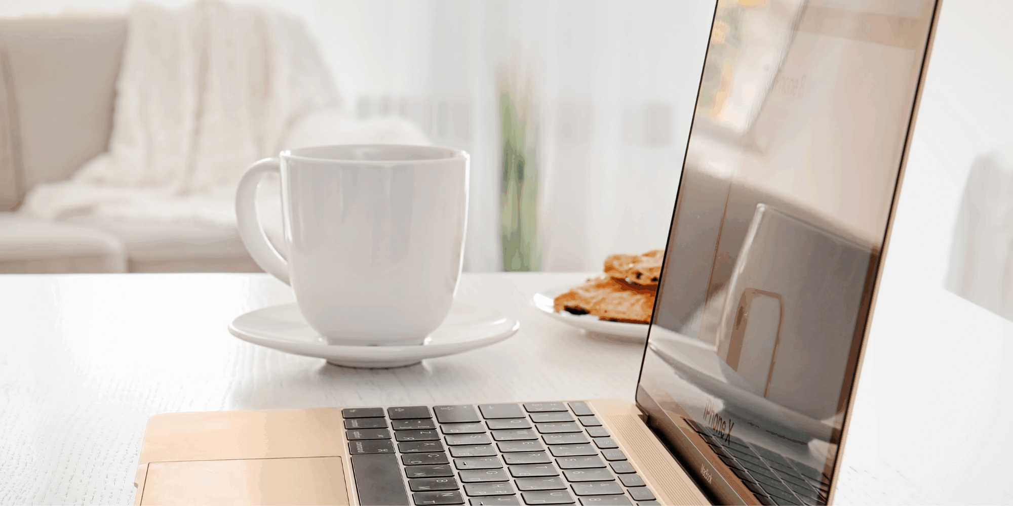 laptop and a white coffee mug on a desk