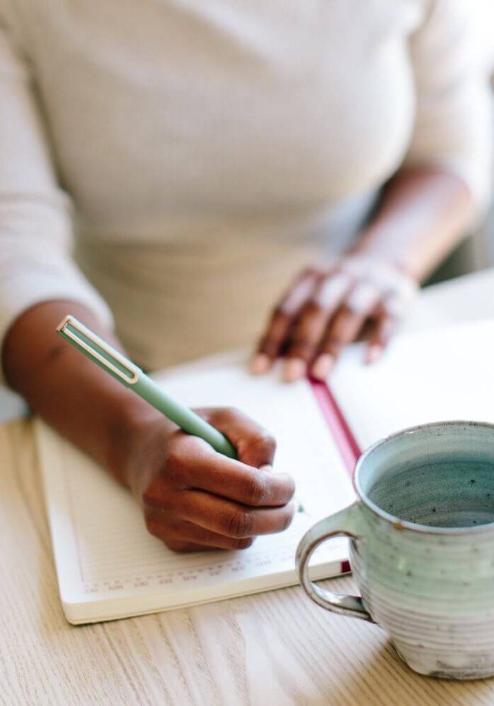 woman journaling with a aqua colored mug on the table