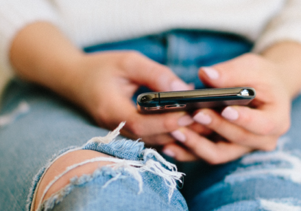 Woman sitting on the floor, looking overwhelmed and exhausted while scrolling on her phone, illustrating the feeling of being "full."