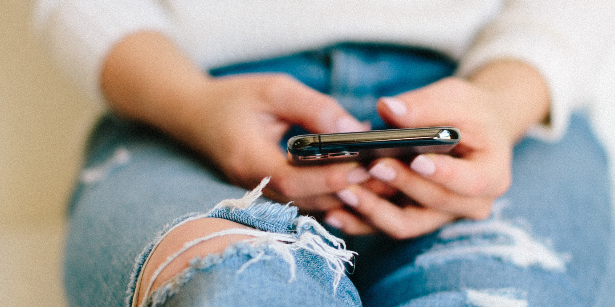 Woman sitting on the floor, looking overwhelmed and exhausted while scrolling on her phone, illustrating the feeling of being "full."